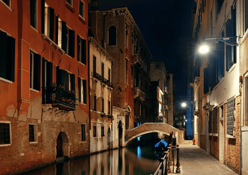 Venice canal reflecting Gothic palace facades at sunset during a crimes and mysteries walking tour in Venice Italy