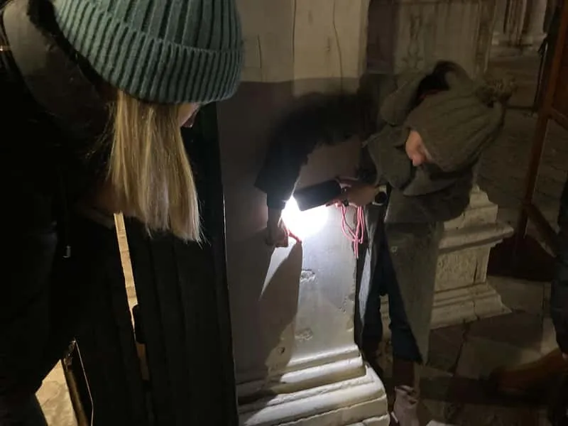 Narrow Venice alleyway lit by lamplight at night during a ghosts and murders mystery walking tour in Venice Italy