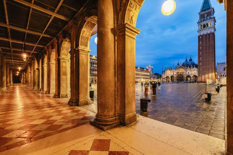 Group of travelers on a ghost and legends walking tour through lamplit Venice streets at night in Venice Italy