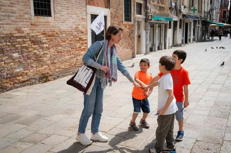 Family with children exploring narrow Venice alleyways at dusk on a ghost hunting adventure tour in Venice Italy